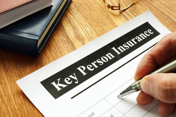 A photo of a person filling out a Key Person Insurance form.