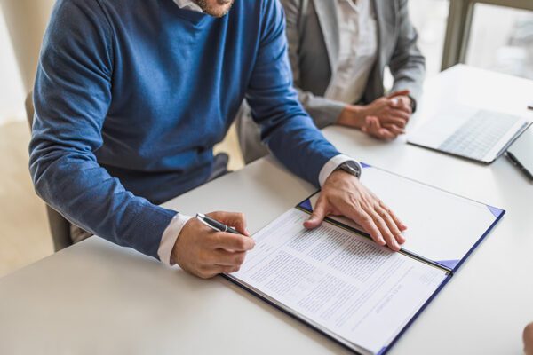 Picture of businessman or entrepreneur in blue sweater, leaving a signature on a document for finance.