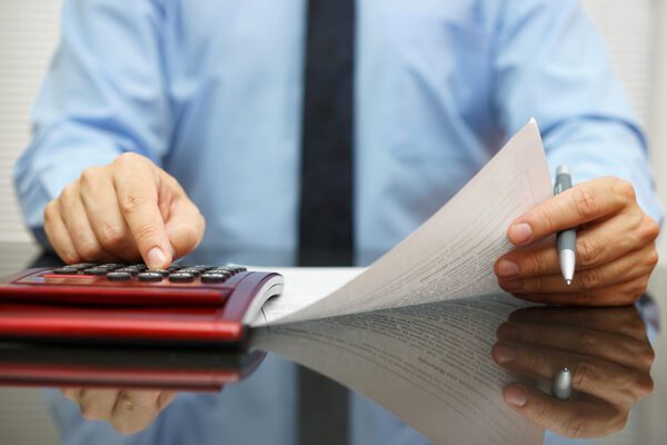 Businessman reading document with numbers and calculating