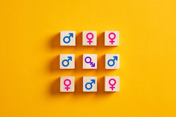 Transgender symbol surrounded with male and female symbols on wooden blocks. Transgender oppression, gender identity and gender expression in society, transgender issues and community concepts.