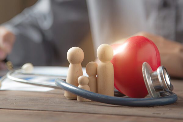 Close up family wooden doll and rad hard and medical stethoscope for insurance planning protection and safety family health concept.